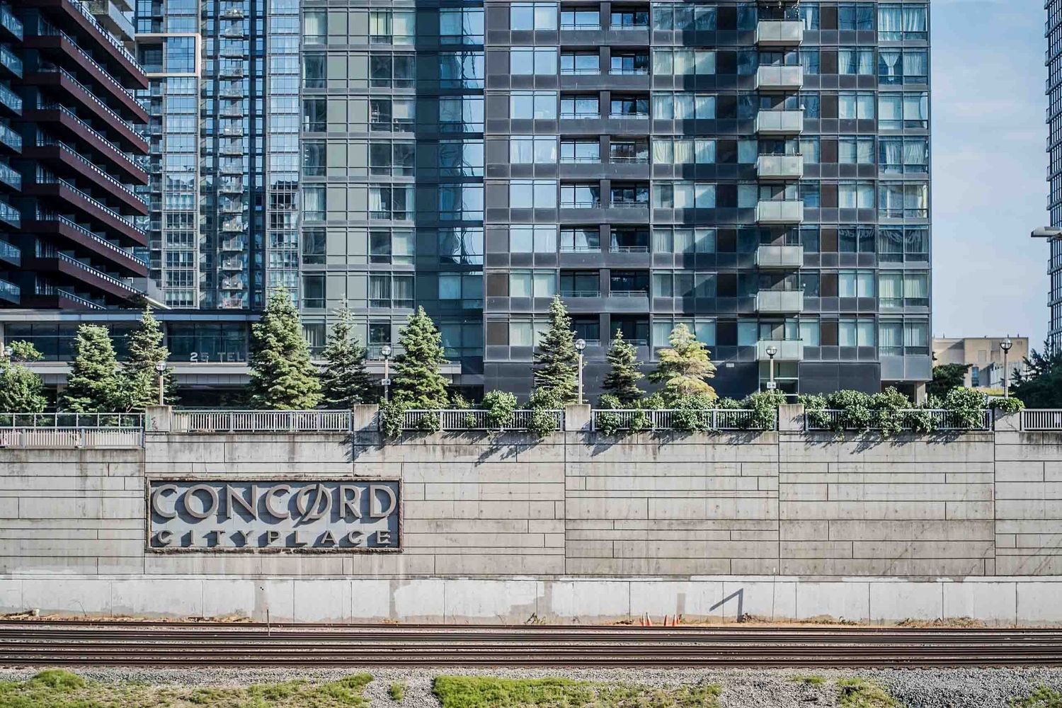 Modern high-rise residential buildings with glass balconies along urban streetscape.