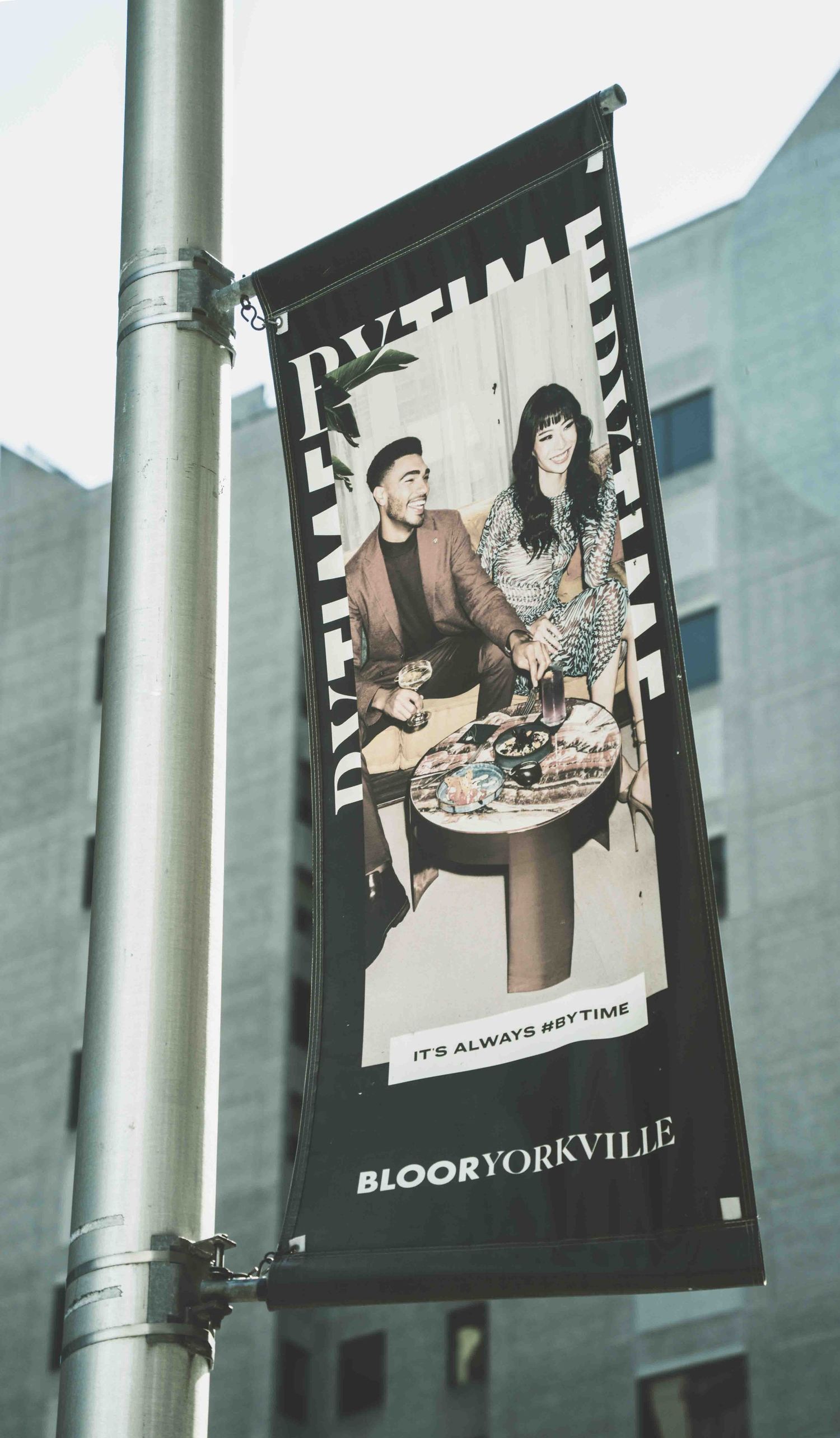 Black and white advertising banners hanging from metal poles in an urban setting.