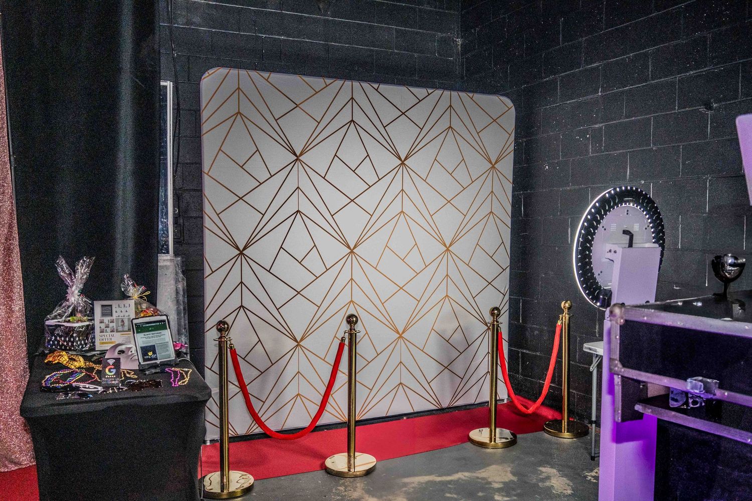 Event space with geometric gold pattern wall design and red velvet ropes.