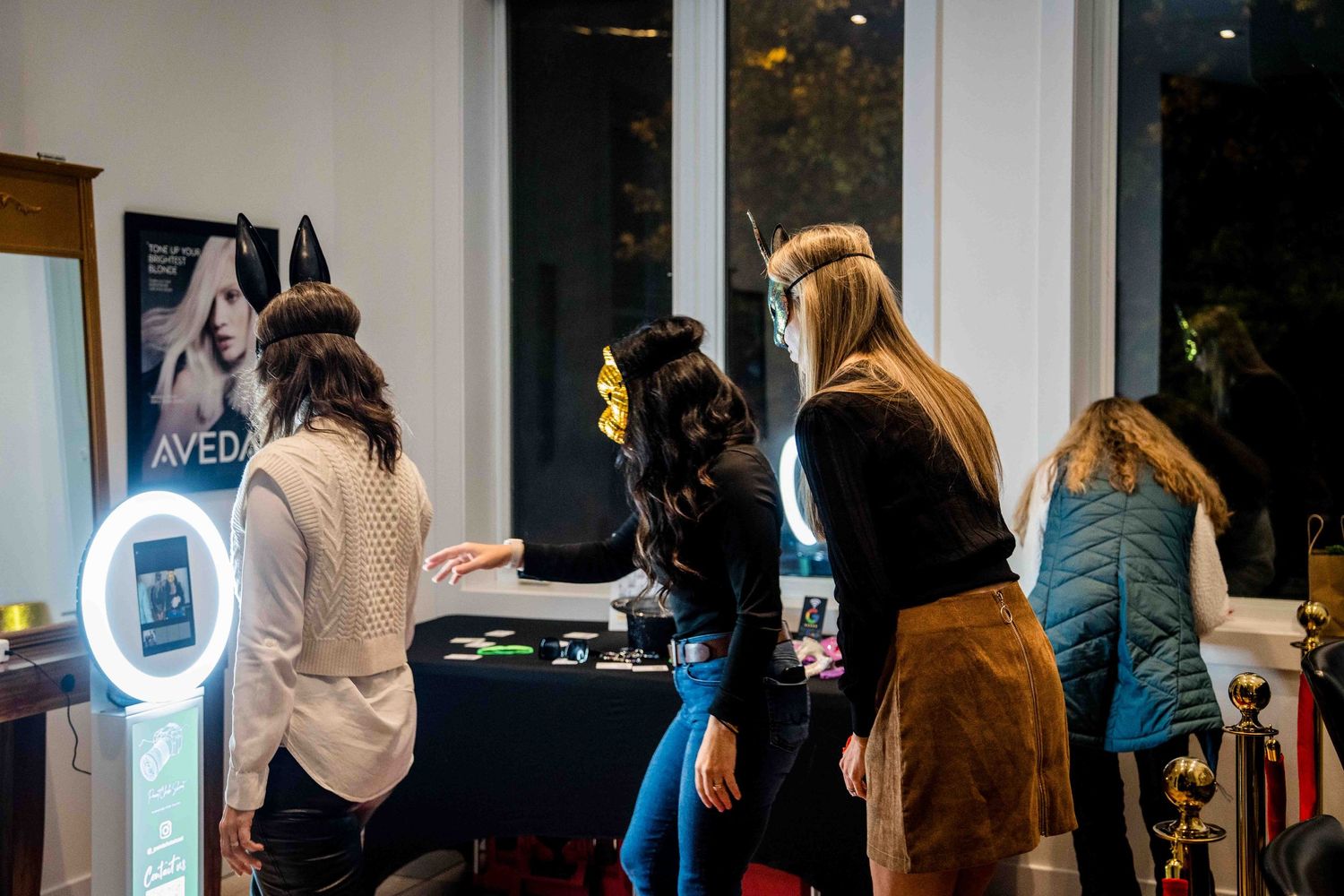 Attendees gathered around illuminated photo booth kiosk at evening event.