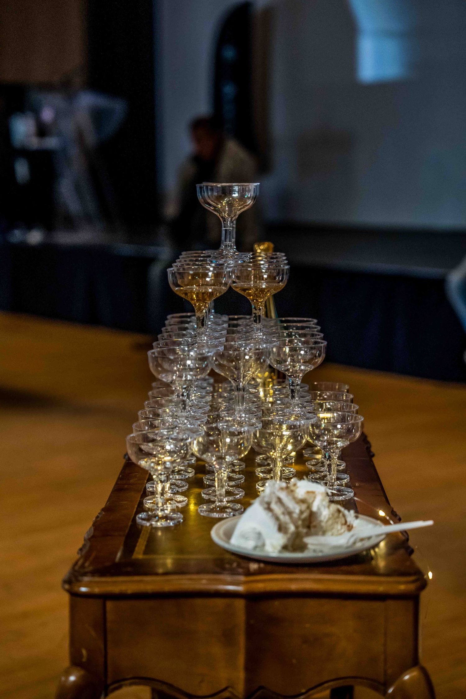 Vintage crystal champagne coupes arranged on a wooden table with soft lighting in a dark room.