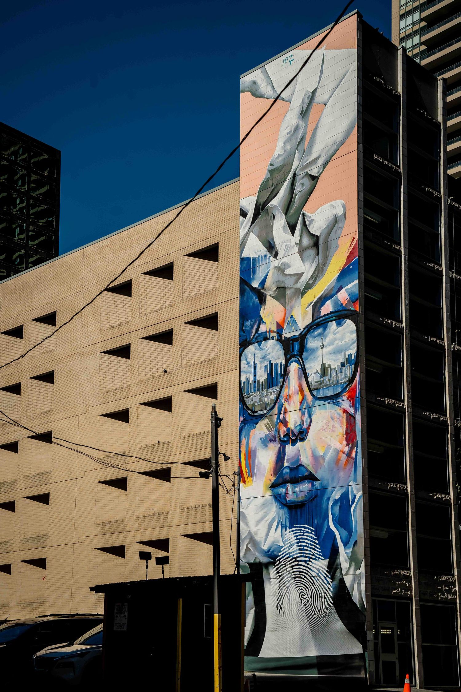 Large urban mural artwork on concrete parking structure wall.