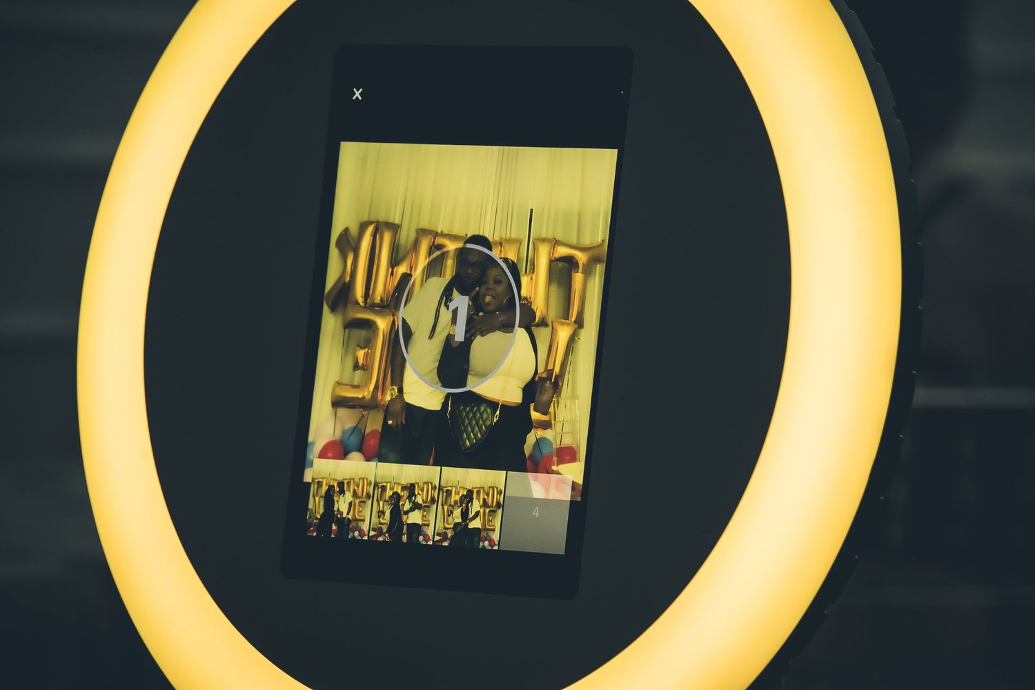 Yellow-tinted ring light displaying digital screens in sequence.