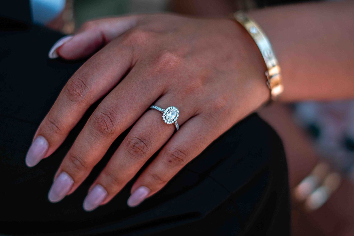 Close-up of a hand wearing a round diamond engagement ring and bracelet.