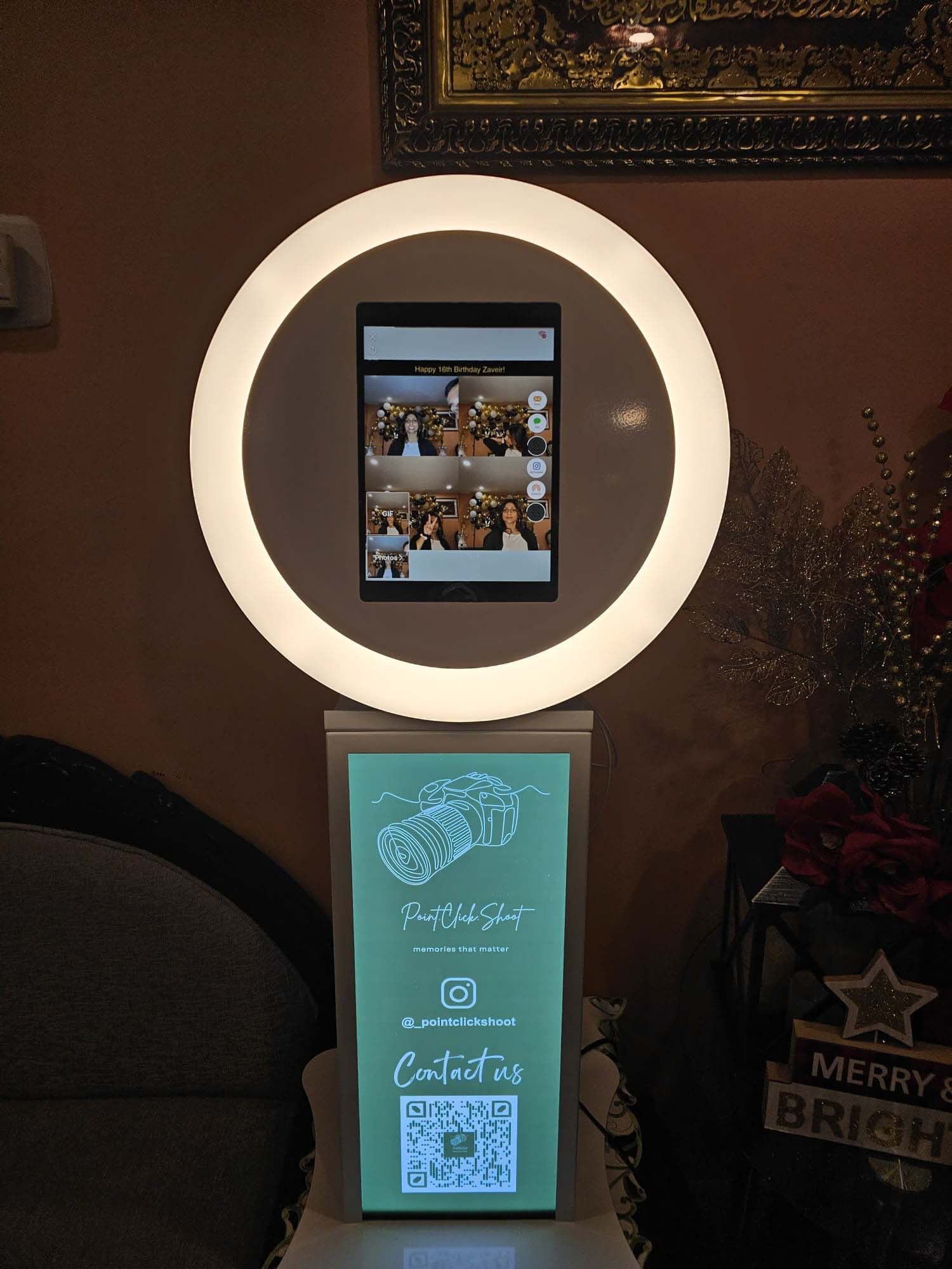 Photo booth display with festive Christmas decorations and circular ring light illumination.