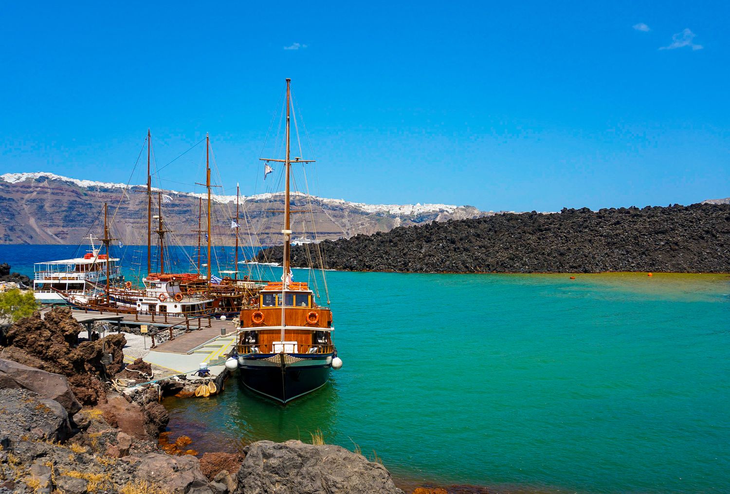 Panoramic view of turquoise waters with boats and mountains in the background.