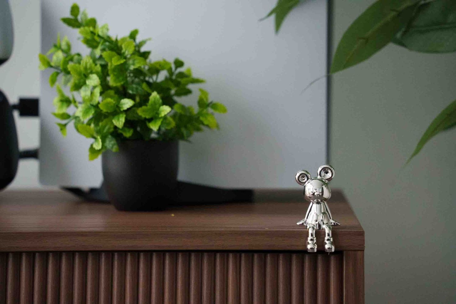 Small decorative plants displayed on wooden furniture with minimalist styling.