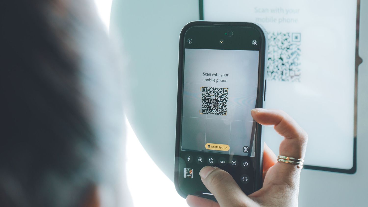 Someone holding a phone to scan QR codes on a wall display.