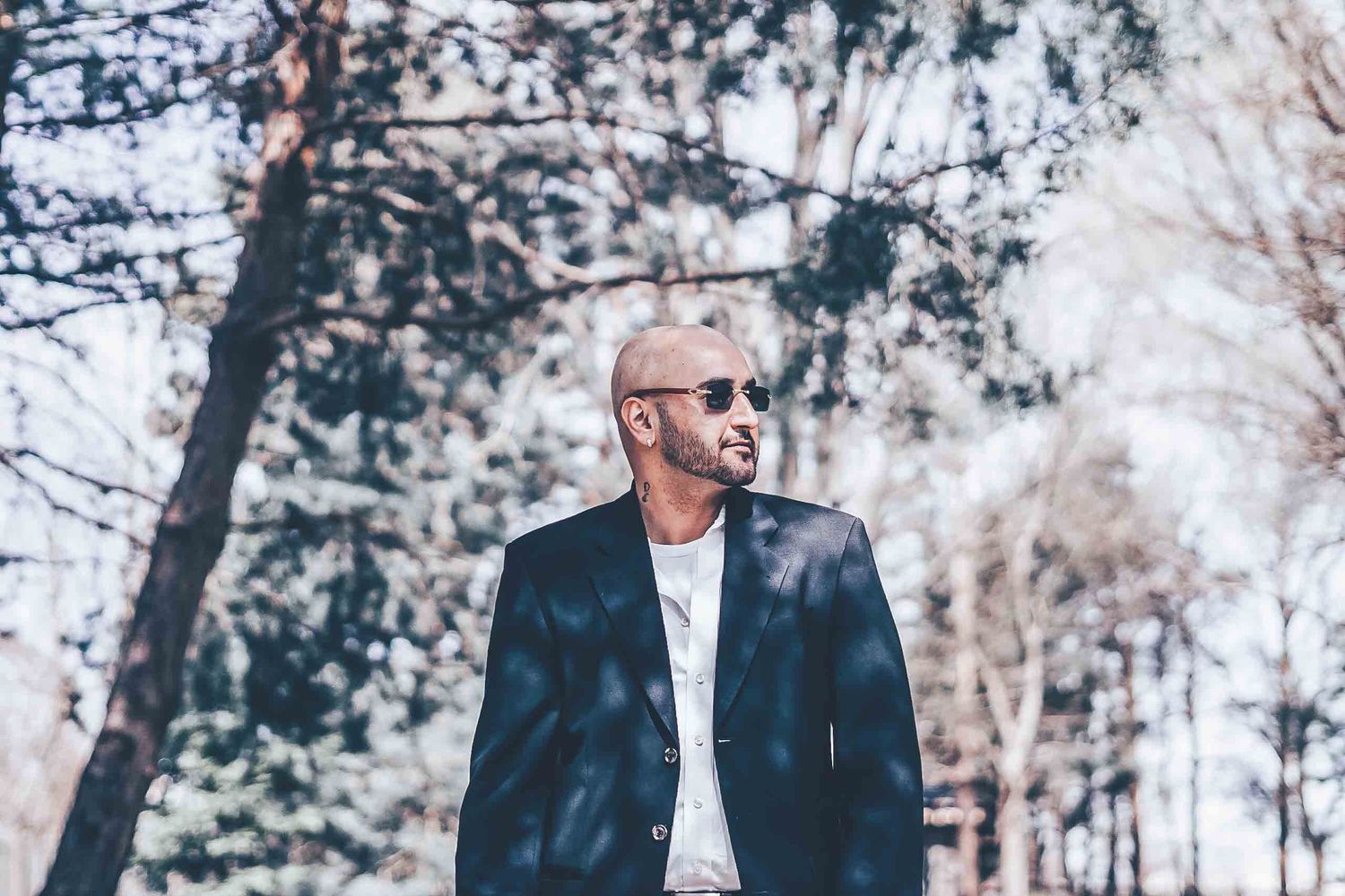 Stylish portrait of person in suit jacket among winter trees.
