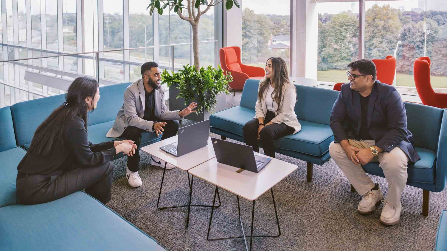 Modern office lounge area with blue couches and collaborative seating arrangements.