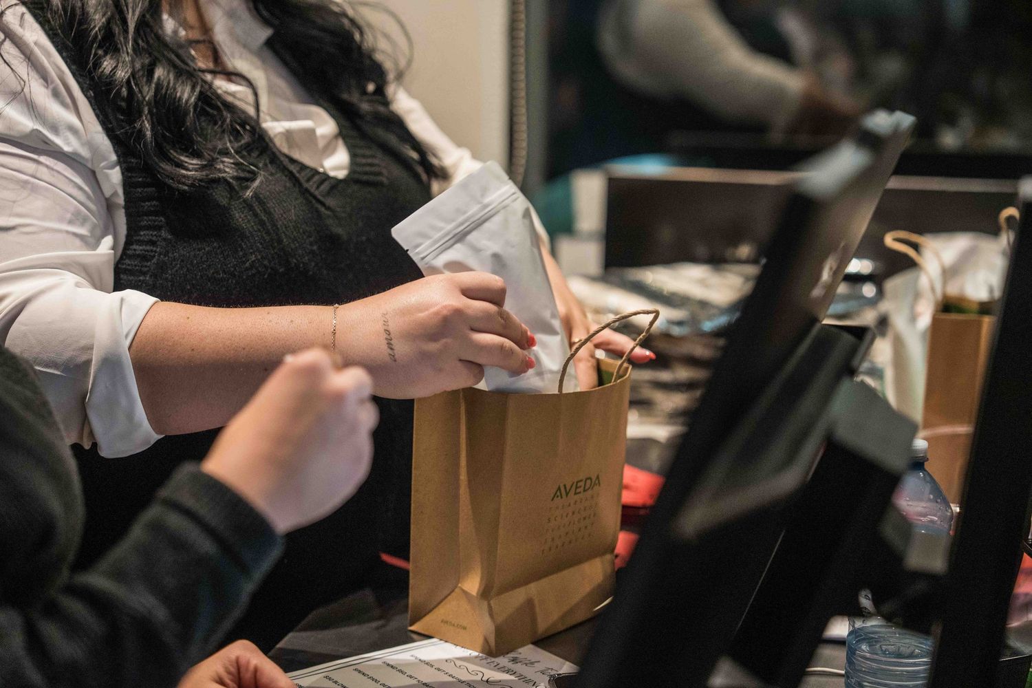 Hands preparing food orders and drinks at a busy restaurant counter.