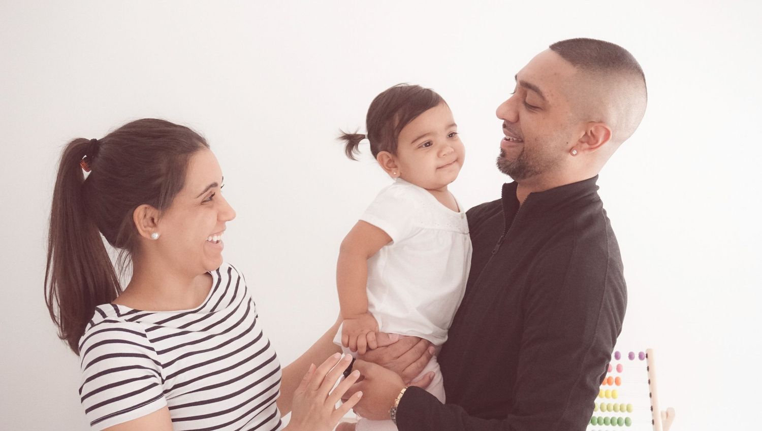 Family portrait series in minimalist white studio setting with striped shirt accents.