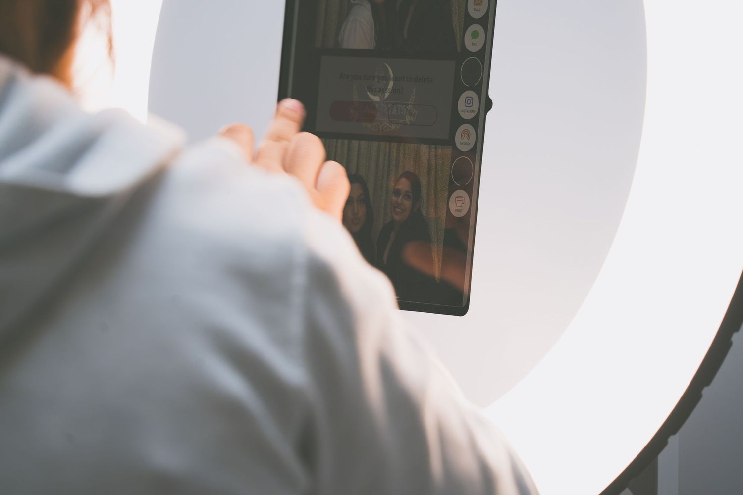 Hands holding a device in front of a bright circular light against a white background.