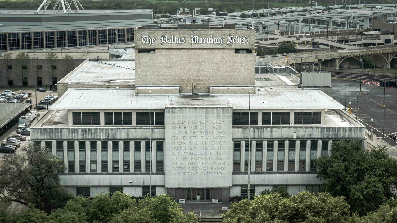 Aerial view of a large government building complex with white concrete architecture and parking lots.