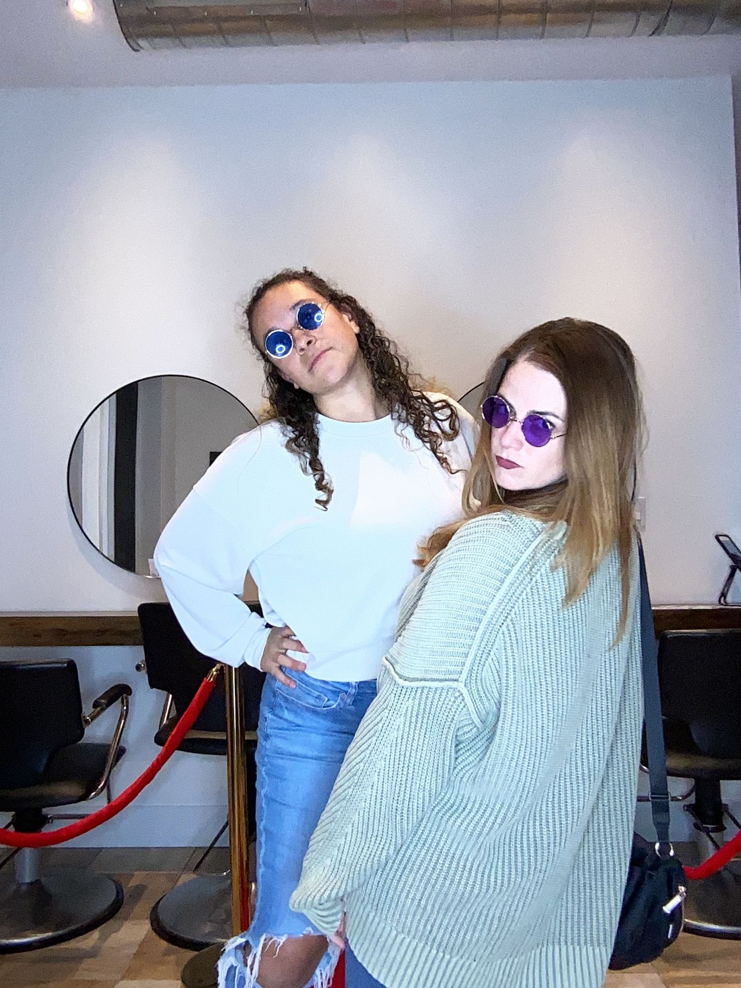 Two friends pose in sunglasses and casual outfits at Romeo Salon.