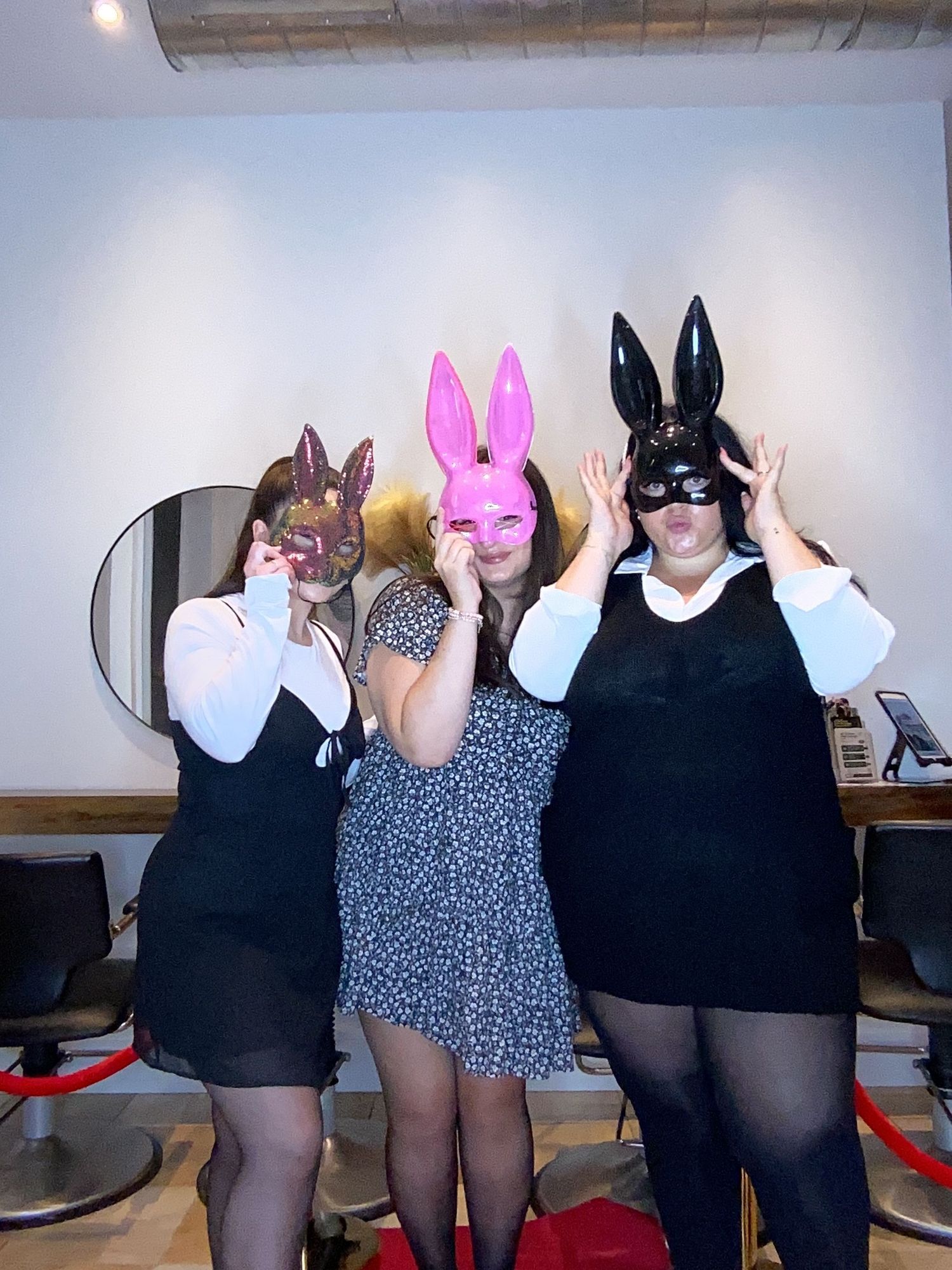 Three people wearing colorful bunny masks pose together at Romeo Salon.