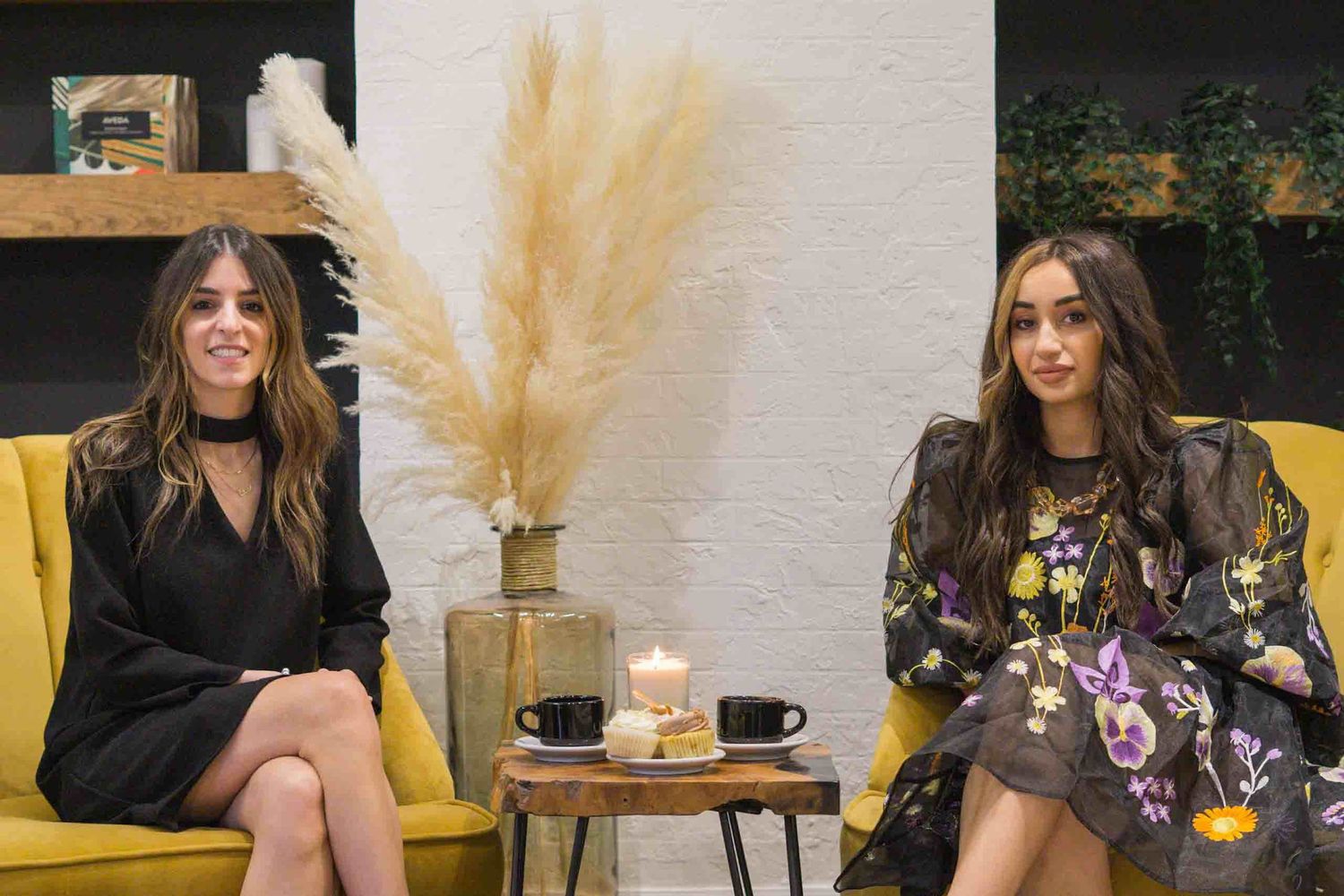Yellow couch and coffee table setup with pampas grass decor in a modern salon space.