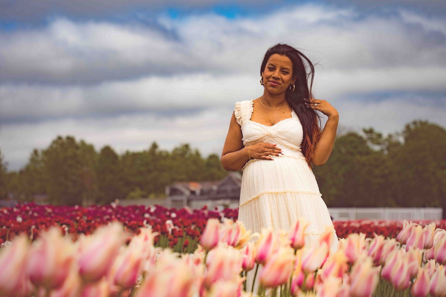 Maternity photo session in beautiful tulip field with pink and red flowers.