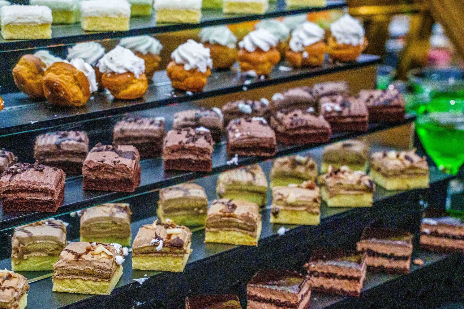 Rows of colorful mini desserts and pastries displayed on black serving platters.