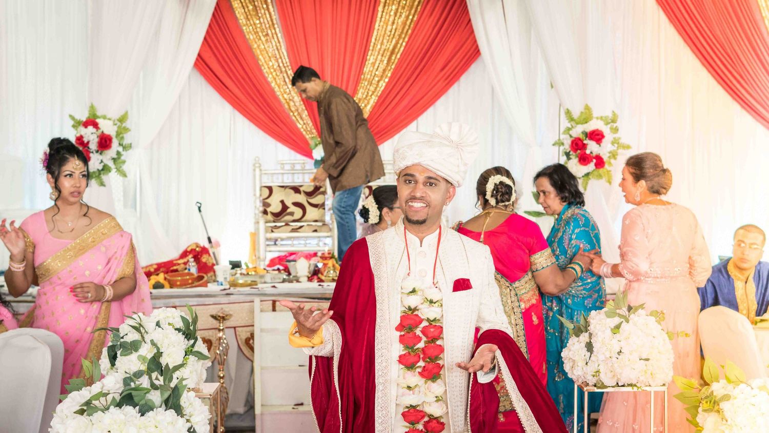 Wedding venue decorated with red and white drapes and floral arrangements.