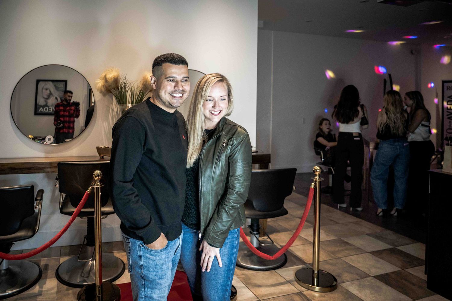 Photo booth area with guests posing in front of backdrop at evening event.