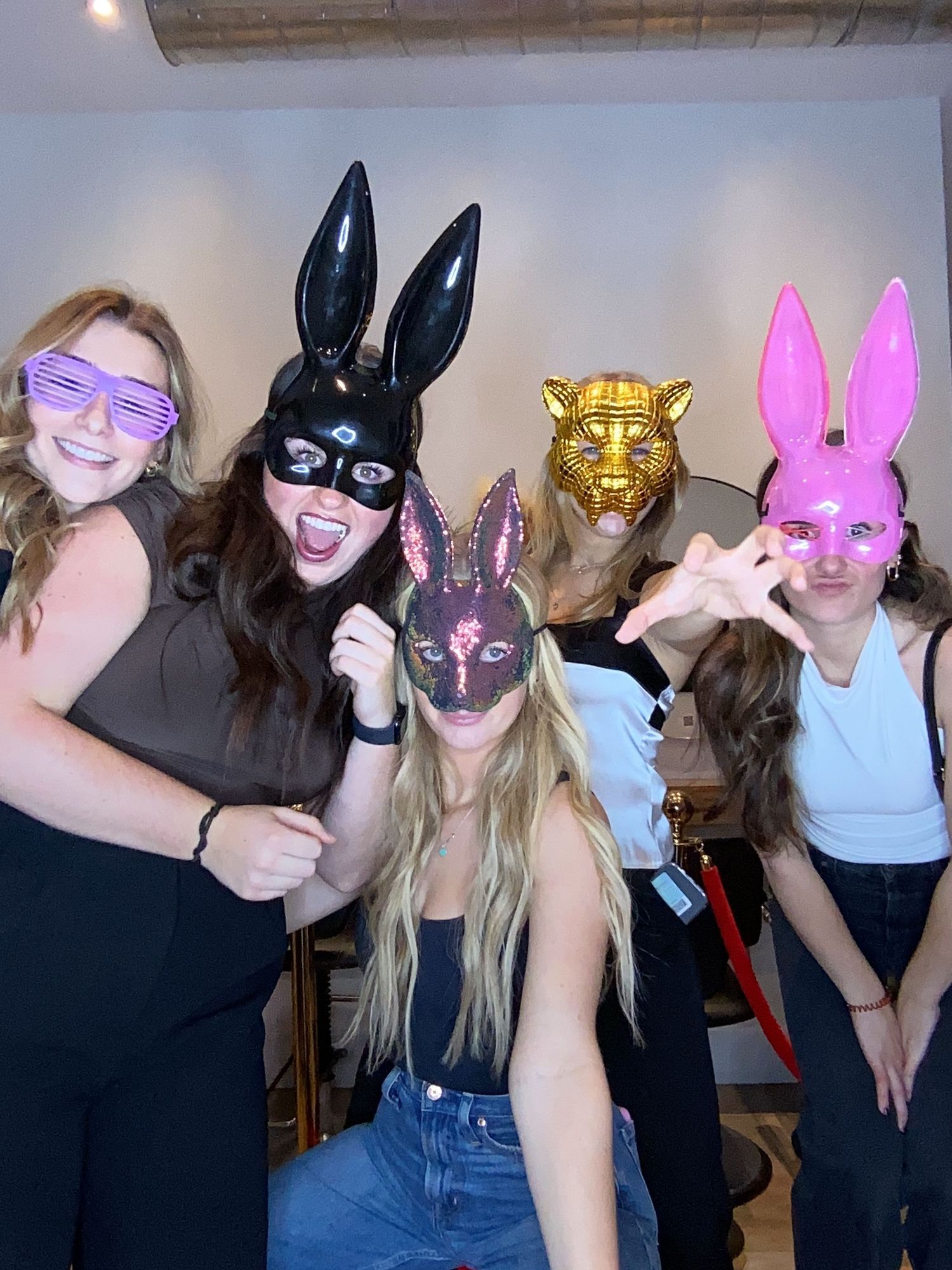 Group wearing colorful animal masks pose playfully at a salon.