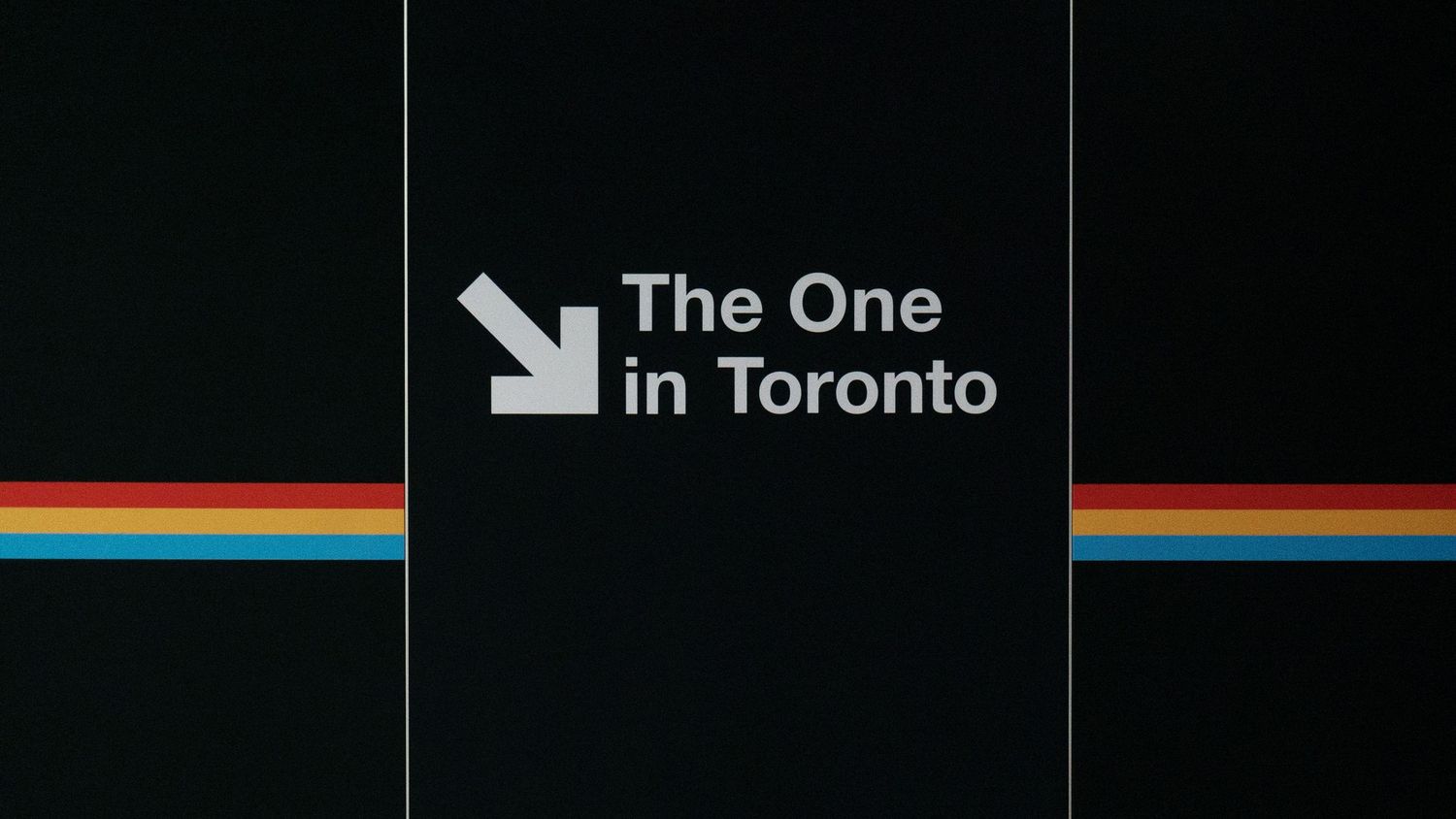 Retro-style graphic design featuring 'The One in Toronto' text with rainbow stripes on black background.