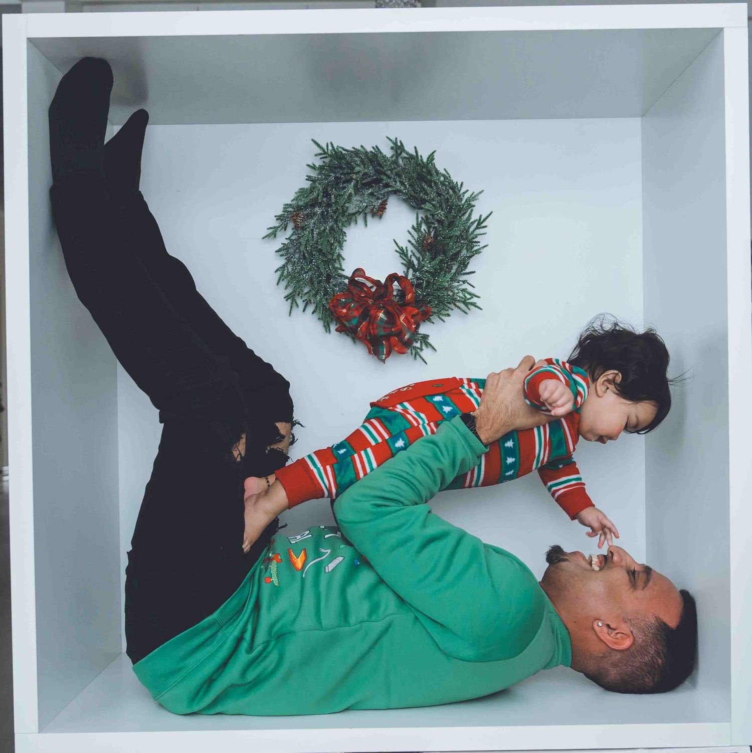 Holiday-themed photos with people lying down near Christmas decorations and wreaths.