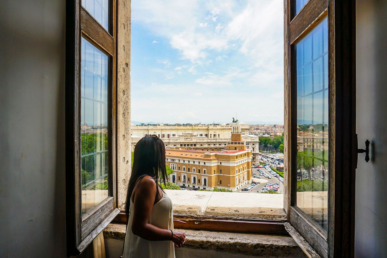 Panoramic window view of city buildings and blue sky through multiple glass panes.