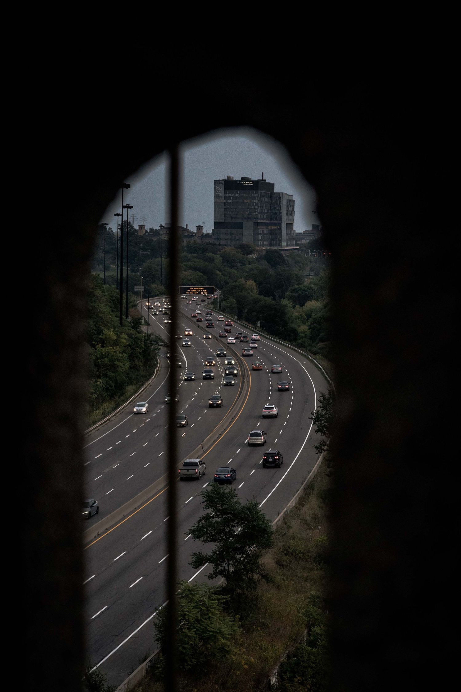 Aerial view of busy highway through city seen through window bars or fence.
