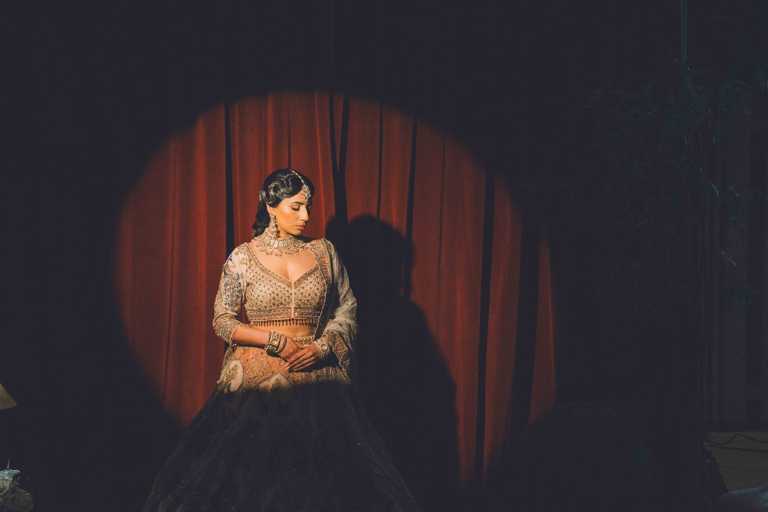 A series of dimly lit stage photos with red curtains showing performers in dramatic lighting.