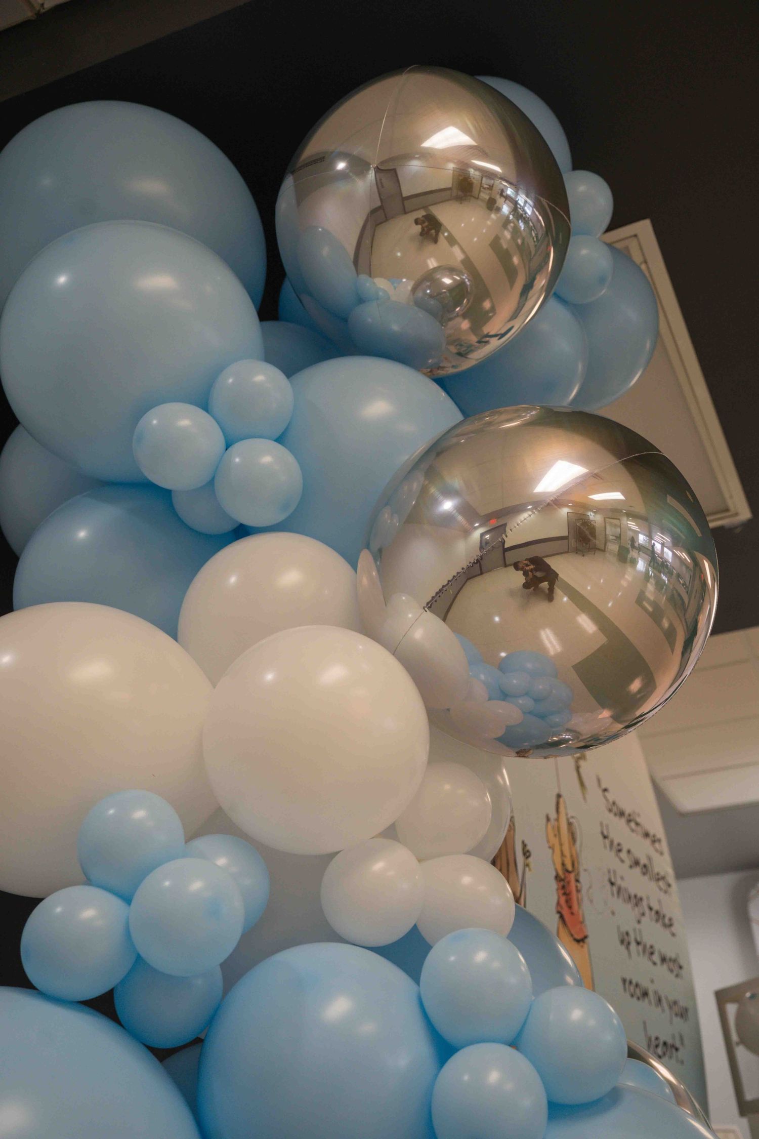 Blue and white balloon garland with silver orbital balloons creating an elegant ceiling decoration.