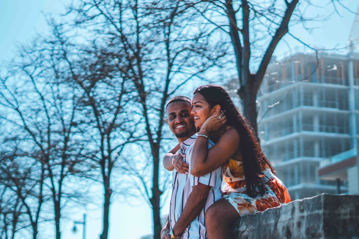 Couple sharing tender moments against a winter urban backdrop with bare trees.