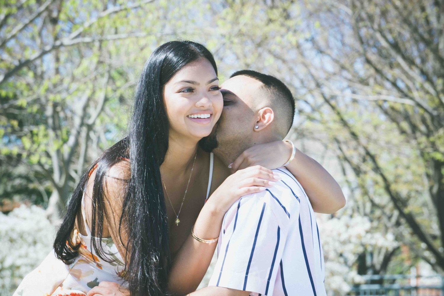 Spring engagement photo session under blooming trees in a park.