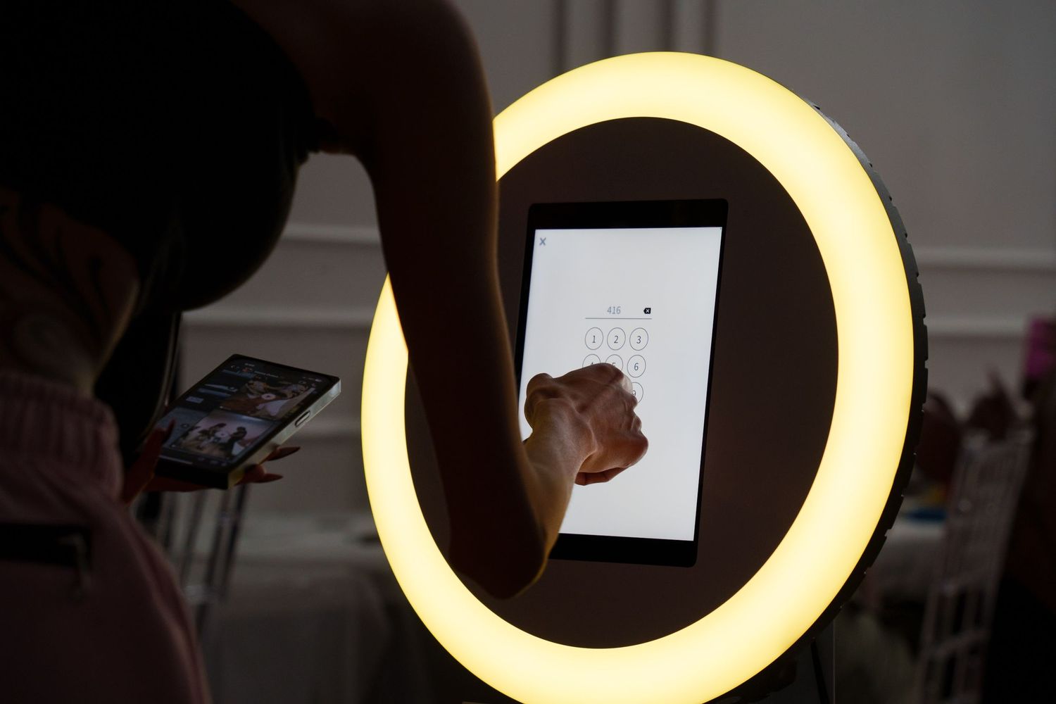 Hand interacting with a tablet device inside a circular ring light.