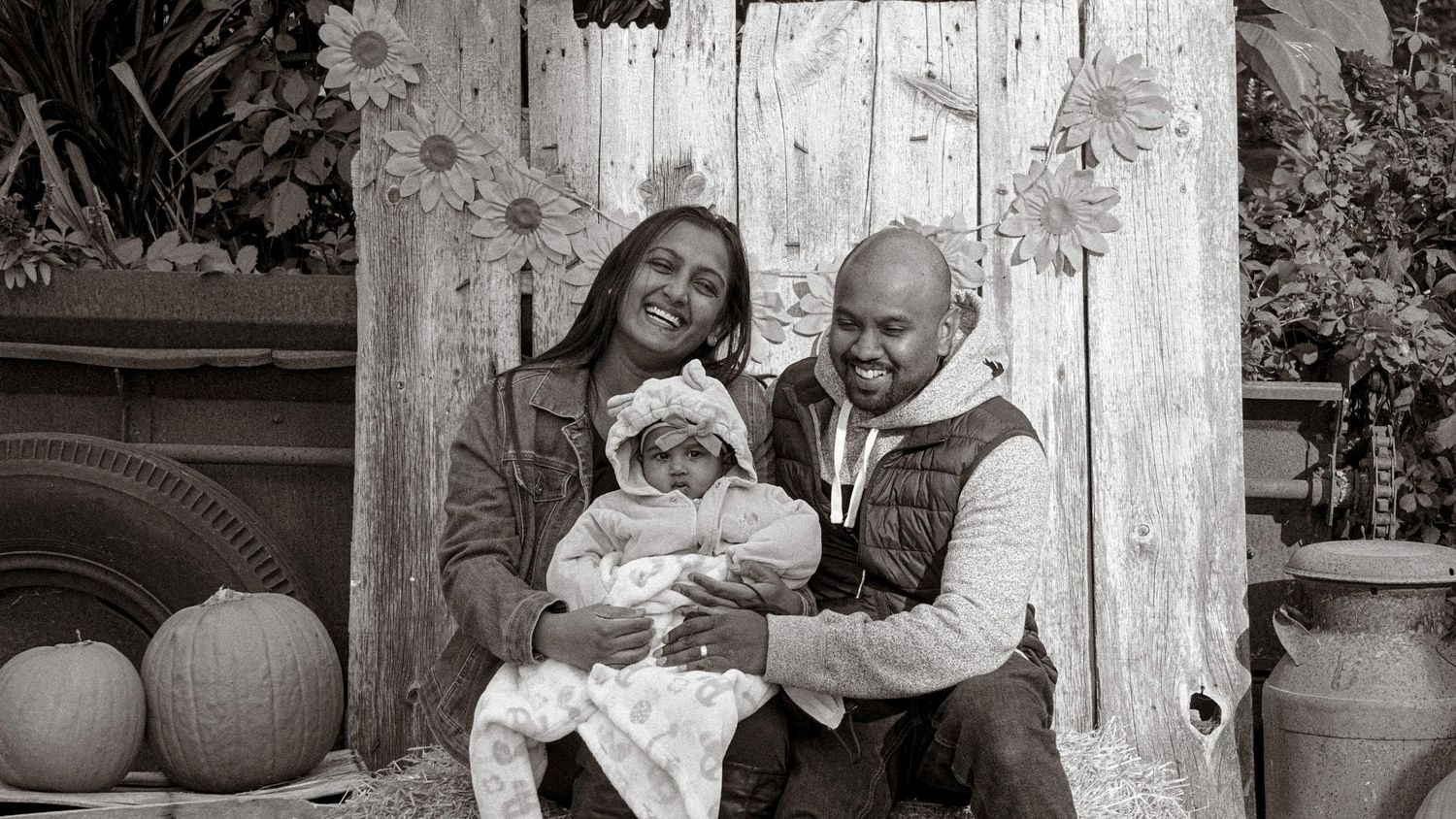 Black and white photo series showing family moments against rustic wooden wall background.