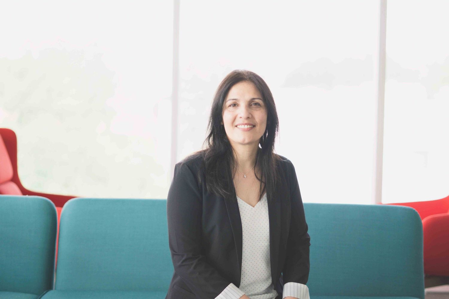 Professional woman in dark blazer photographed in modern office setting.