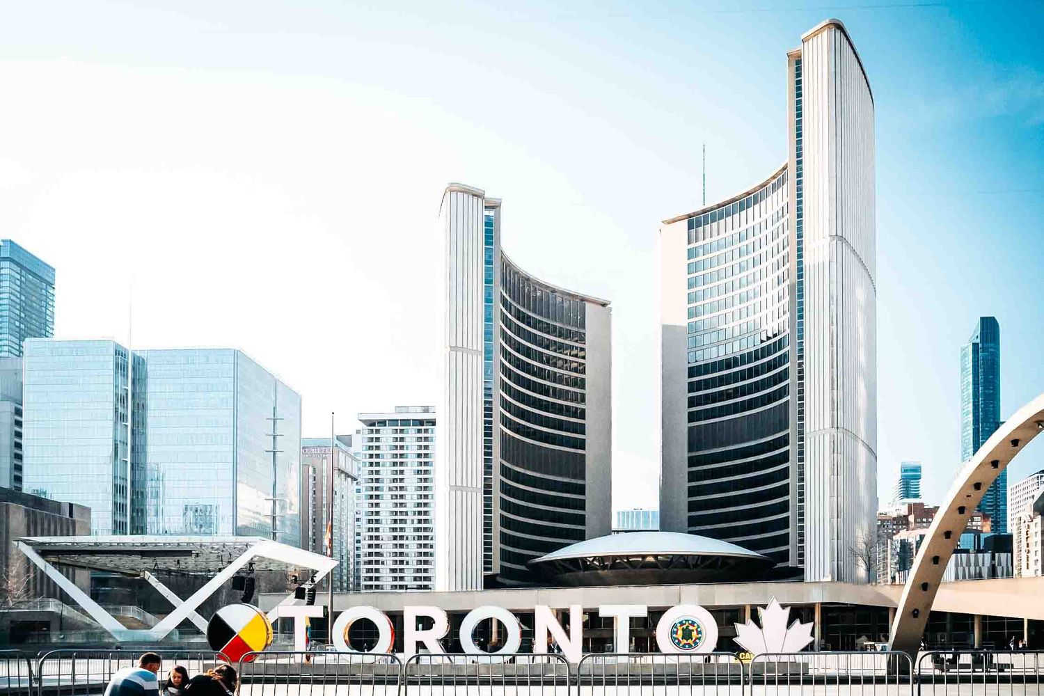Toronto city skyline featuring modern buildings and iconic City Hall with Toronto sign.