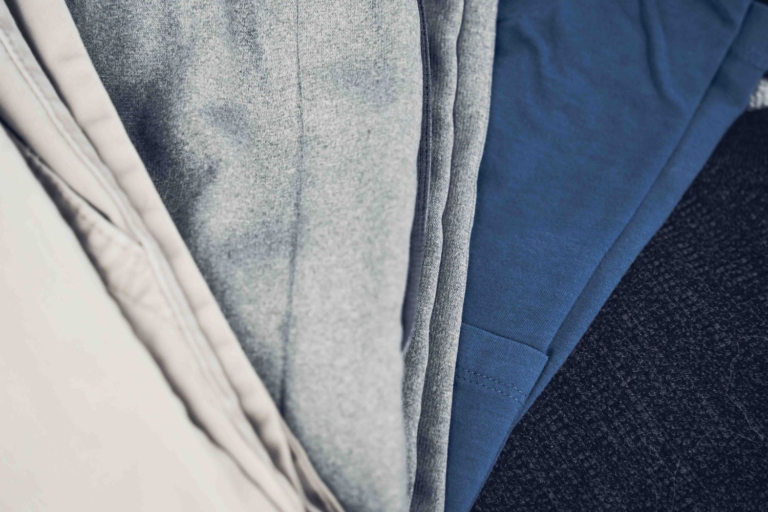Neatly folded blue and gray fabric swatches arranged in overlapping layers on a dark surface.