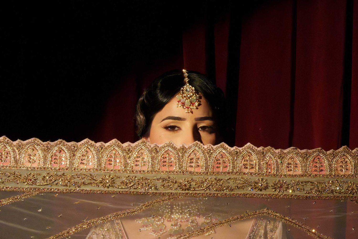 A golden ornate crown detail on red velvet fabric shows intricate metalwork and jeweled embellishments.