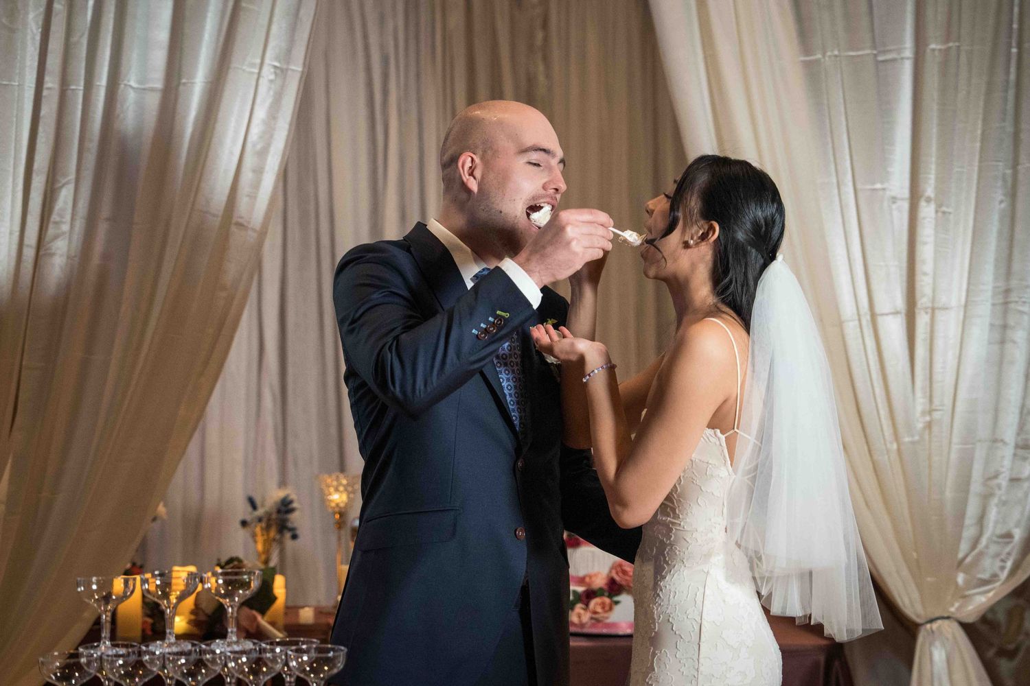 A romantic wedding dance moment with the couple embracing in front of white curtains.