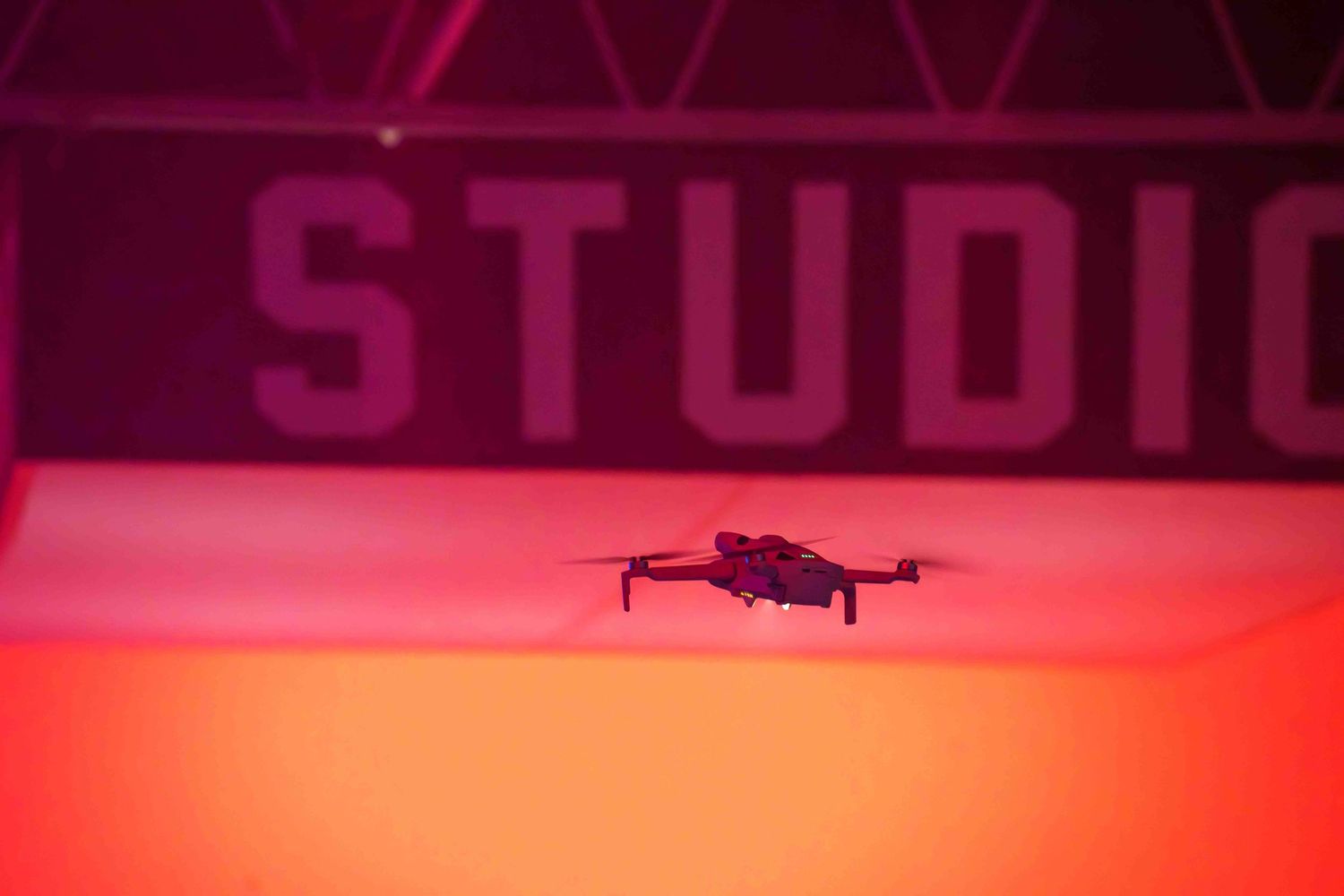 Aerial drone flying against a vibrant pink and red illuminated backdrop.