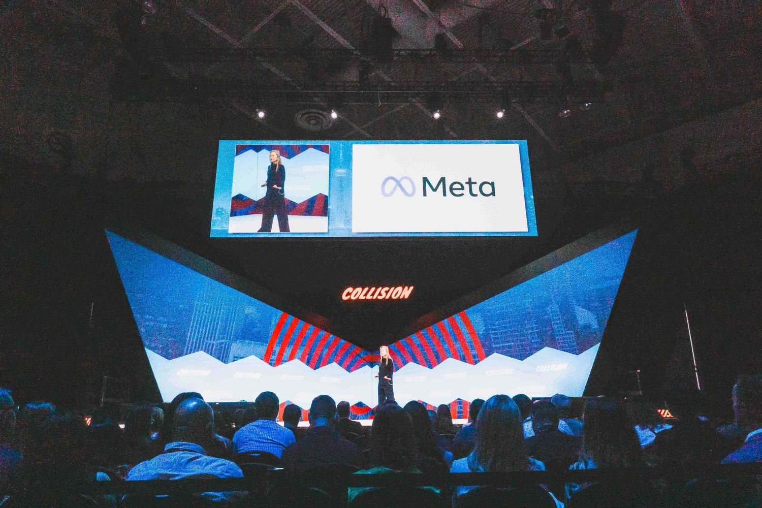 Large indoor event space with dramatic stage lighting and digital displays.