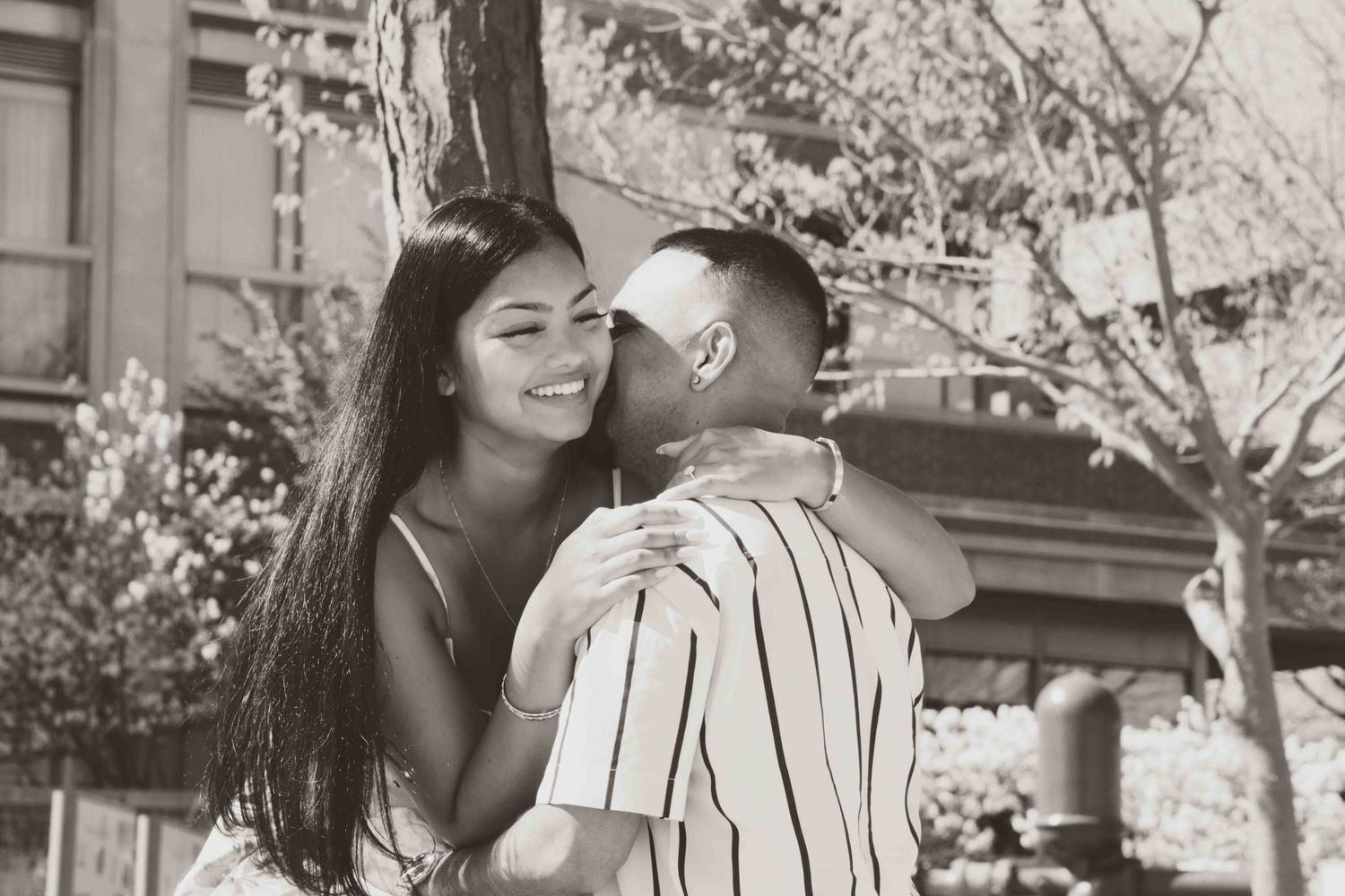 Romantic black and white photo of couple embracing outdoors.