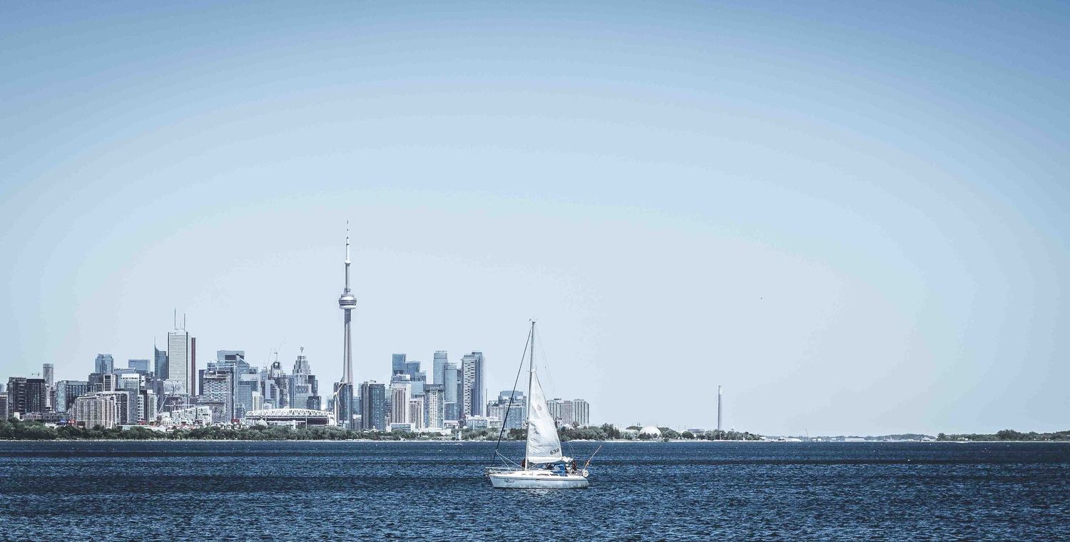 Toronto's distinctive skyline with CN Tower viewed from across calm waters.