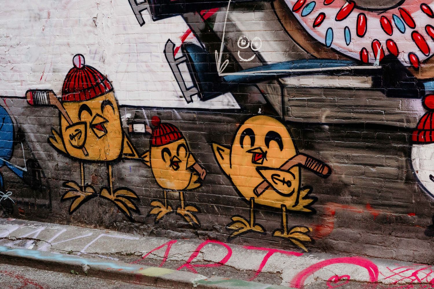 Street art graffiti featuring cartoon-style faces painted on a wooden surface.