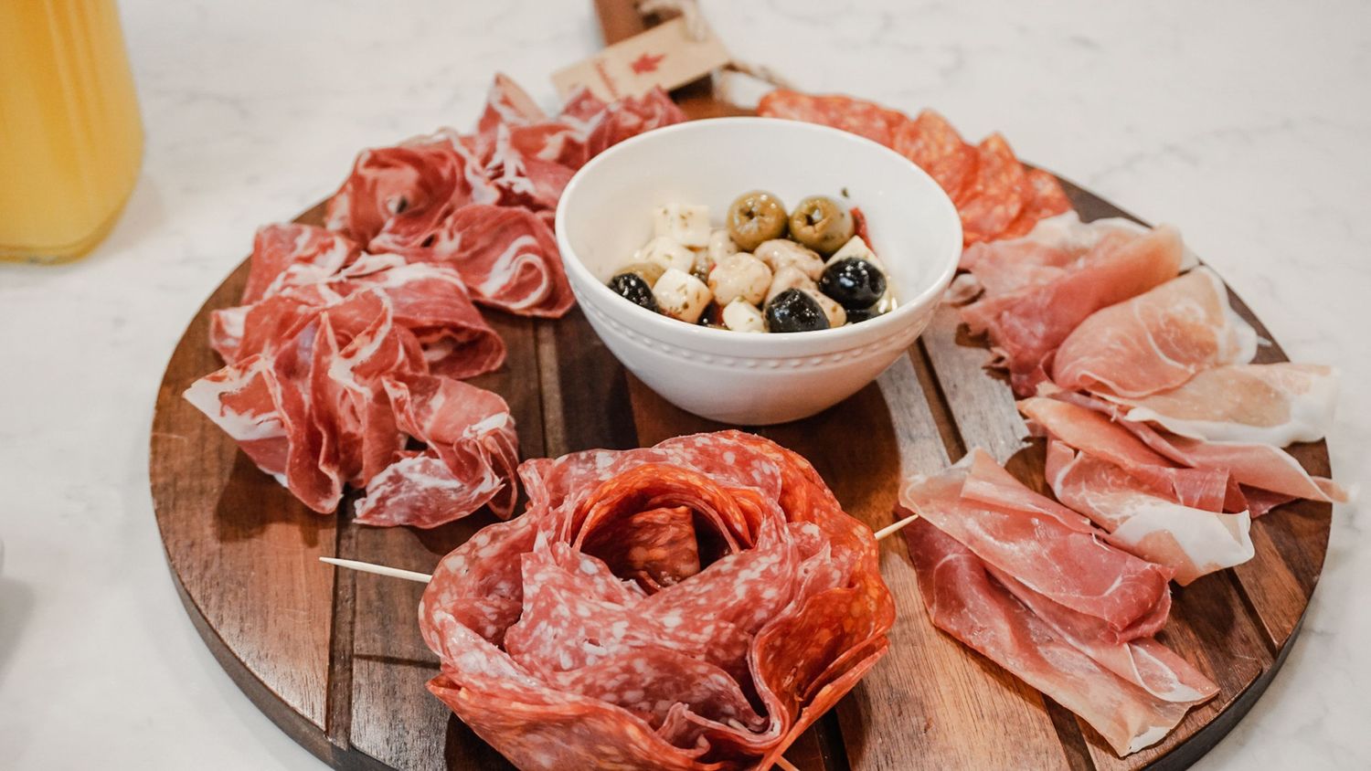 Charcuterie board with assorted cured meats and accompaniments arranged on a wooden surface.