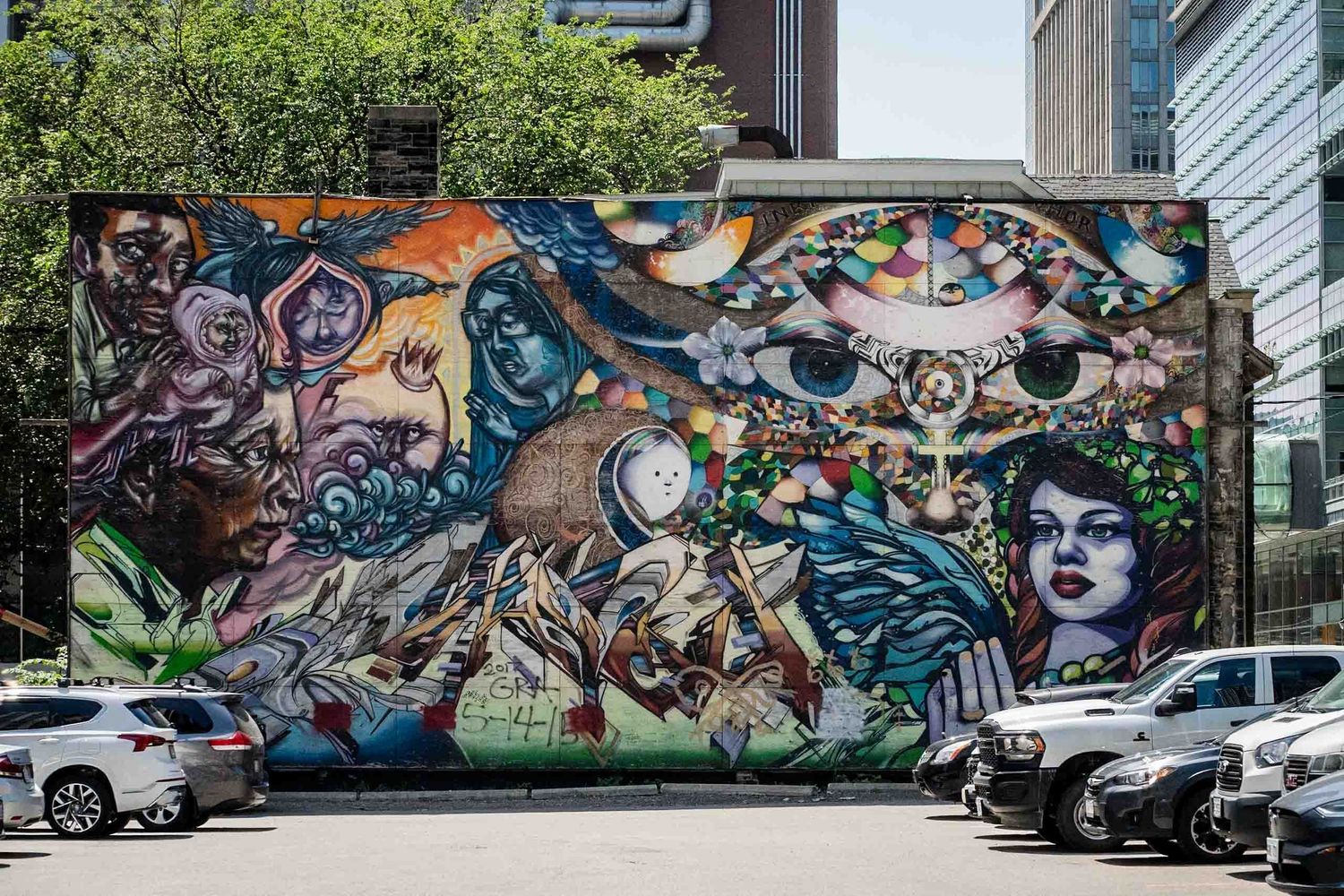 Series of vibrant street art murals decorating an urban parking area with cars.