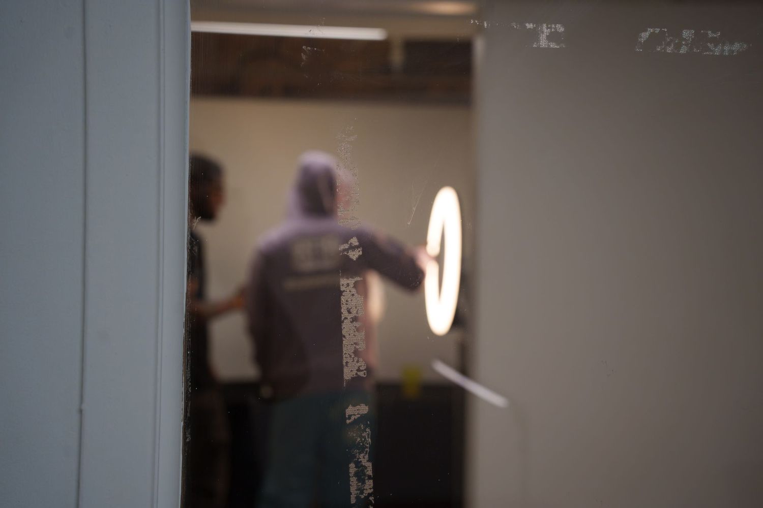 Blurred silhouette of person standing near a glowing circular light fixture.