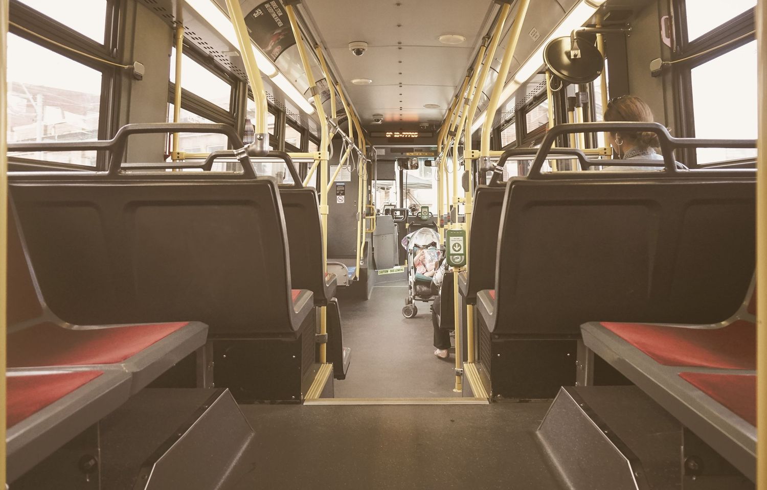 Empty subway car interior with rows of seats and fluorescent lighting.